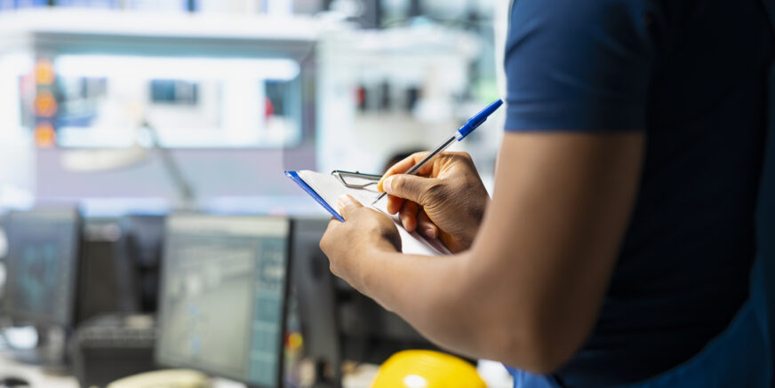 Solar panel manufacturing plant researcher taking notes on files, developing new solar energy systems prototypes. Engineer inspecting new photovoltaics materials, writing down info.