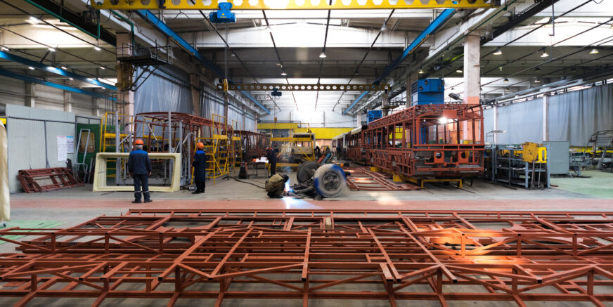 One working day of modern automatic bus trolleybus car production with unfinished cars workers in protective uniform in factory background automobile assembly line welding arm