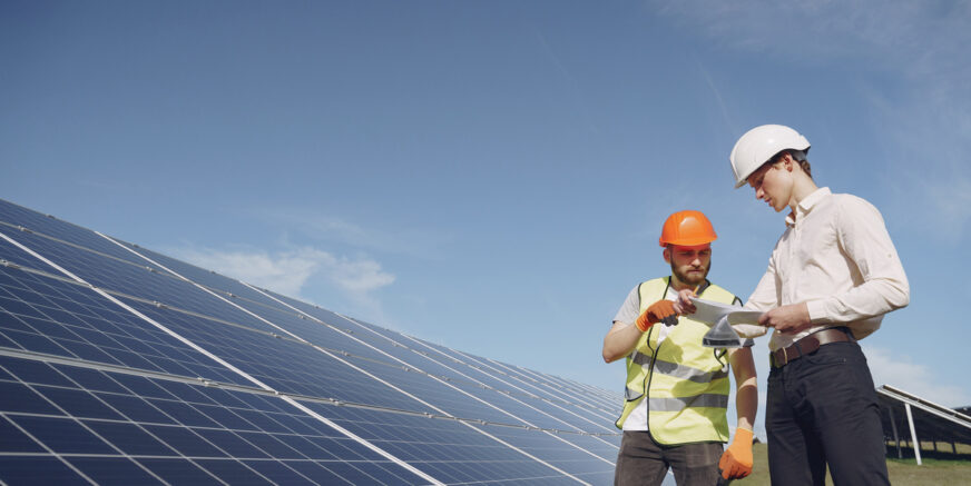 Businessman and worker near solar energy batteries. Business client showing photovoltaic detail to foreman. Two men making deal.